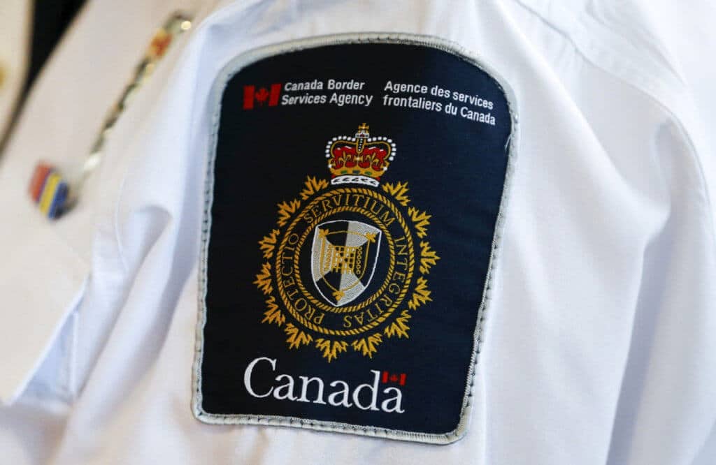 A Canada Border Services Agency (CBSA) logo is seen on a worker 